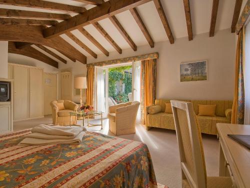 Hotel Tamaro في أسكونا: غرفة نوم مع سرير وغرفة معيشة