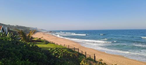 a beach with a fence next to the ocean at Seaside Serenity - Your ultimate beachfront escape in Sheffield Beach