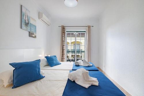 una camera con 2 letti con cuscini blu e una finestra di Monte Fino Beach a Monte Gordo