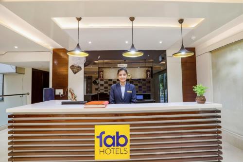 FabHotel Grand Stay في نيودلهي: امرأة تقف خلف مكتب الاستقبال في فندق