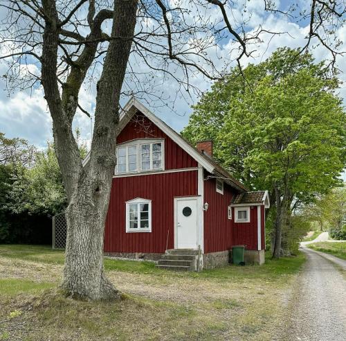 a red barn with a tree in front of it at Traditional Red House By The Lake In Småland in Åby