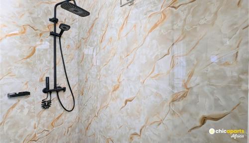 a shower in a bathroom with a stone wall at Chic apart with parking and rooftop in Yaoundé