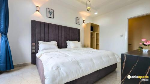 a bedroom with a large bed with a wooden headboard at Chic apart with parking and rooftop in Yaoundé