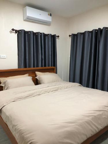 een slaapkamer met een groot bed met blauwe gordijnen bij The Sun homestay in Ko Kood