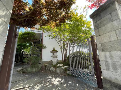 a gate to a house with a fence and trees at 木の家ゲストハウス小山西口館 in Oyama