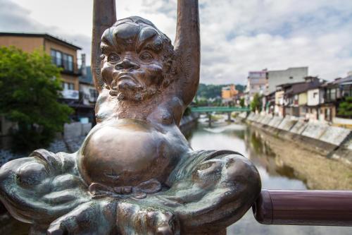 a statue of a little girl standing next to a river at Honjin Hiranoya Kachoan in Takayama