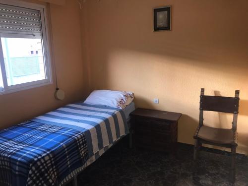a bedroom with a bed and a chair and a window at Piso Alicante in Alicante