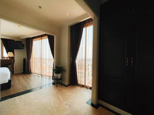 a bedroom with a bed and windows with a potted plant at Maccal Boutique Hotel Dalat in Da Lat