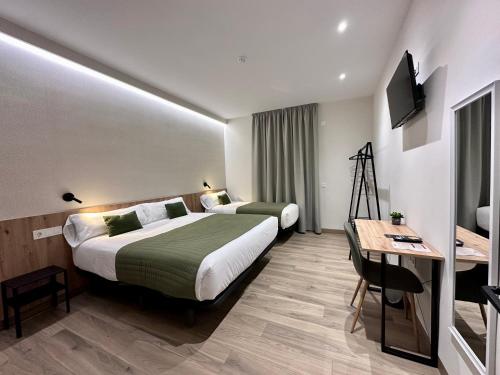 a hotel room with two beds and a desk at Hotel Síbel Baza in Baza