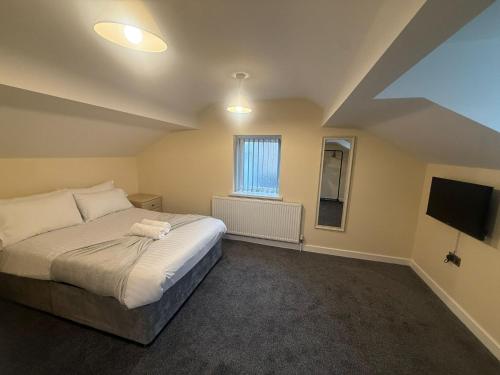 a bedroom with a large bed and a television at Rose Cottage by Sasco in Blackpool