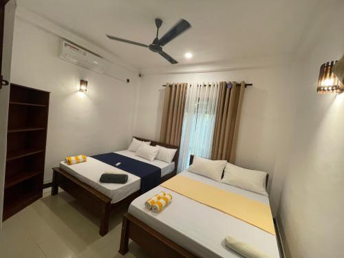 a bedroom with two beds and a ceiling fan at Delight Villa - Ahangama in Ahangama