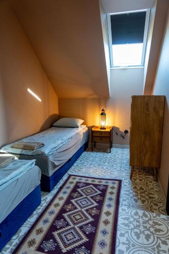 two beds in a room with a window and a rug at La Jura in Podlesice