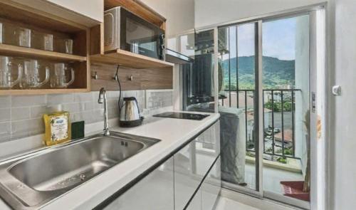 a kitchen with a sink and a large window at Dcondo Kathu - Top Floor 1 Bdr Condo with shared Pool in Kathu