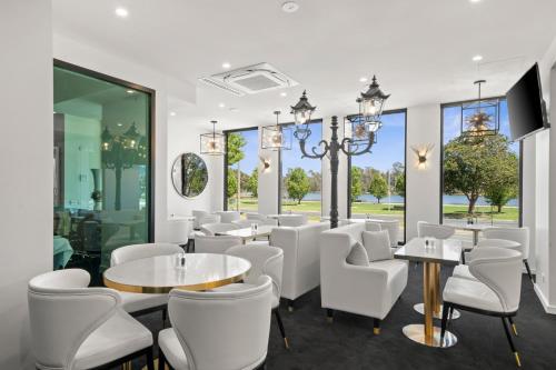a restaurant with white chairs and tables and windows at The Carrington Hotel in Shepparton