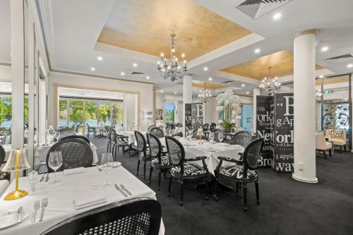 a dining room with white tables and black chairs at The Carrington Hotel in Shepparton