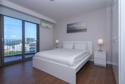 Un dormitorio blanco con una cama y una ventana grande. en Pine City Residence, en Kusadasi