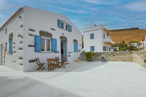 a white building with blue windows and a table at Stylish villa Antika close to the shops and restaurants in Korissia, Kea in Korissia