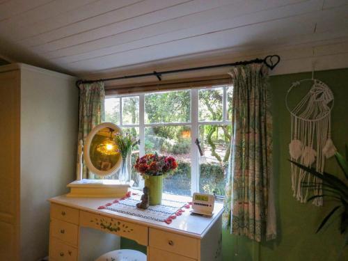 a window with a dresser and a mirror and flowers at Bluebell Cottage At Lurley Manor in Washfield