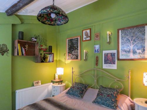 a bedroom with green walls and a bed and a chandelier at Bluebell Cottage At Lurley Manor in Washfield