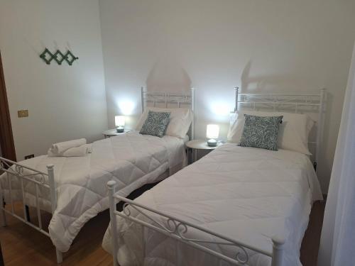 VECCHIA FERROVIA Orvieto Apartment في أورفييتو سكالو: سريرين توأم في غرفة بها مصباحين