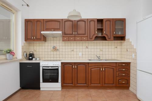 a kitchen with wooden cabinets and a black and white appliance at Pool & Cozy Apartment Warszawa Bukowińska by Solarento in Warsaw