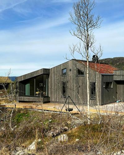 an old building with a large window and a tree at Stylish Mountain Cabin In Hallingdalen in Flå