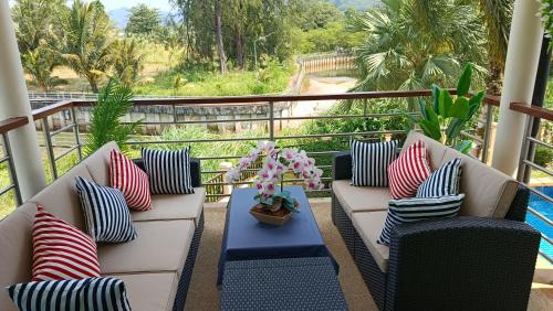 a balcony with two couches and a table with pillows at Wonderful Beach Villa, Perfect Location in Khao Lak
