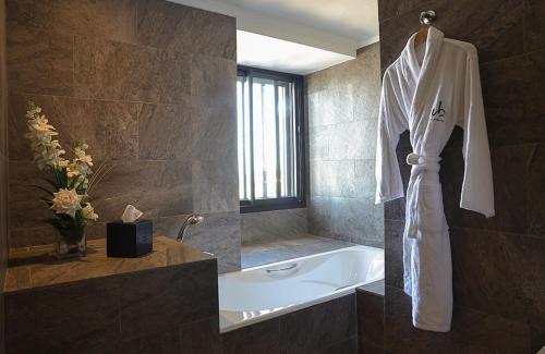 a bathroom with a bath tub and a white robe at Villa Blanca Urban Hotel in Casablanca