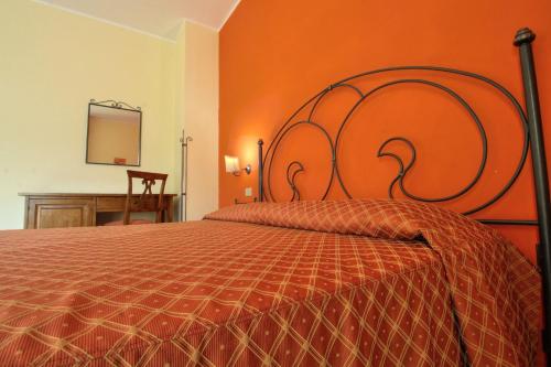 a bedroom with a large bed with an orange wall at Zingaro Hotel in San Vito lo Capo
