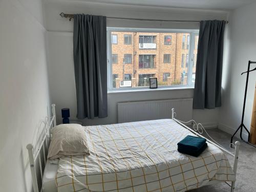 a bedroom with a bed and a large window at Spacious 4 bedroom apartment with parking in Leavesden Green