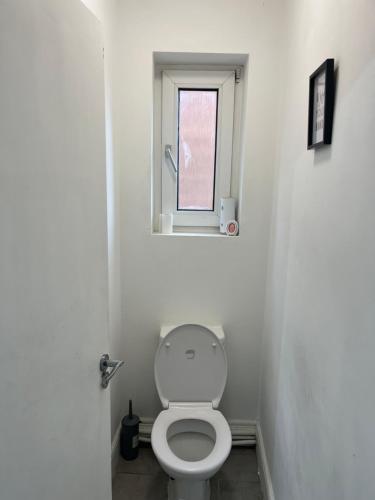 a bathroom with a toilet and a window at Spacious 4 bedroom apartment with parking in Leavesden Green