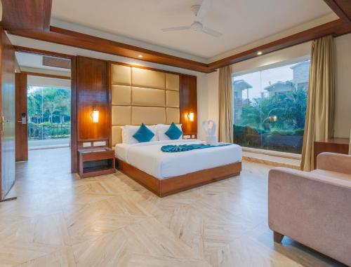 a bedroom with a bed and a large window at Trinantara Resort & Spa in Kālāgarh