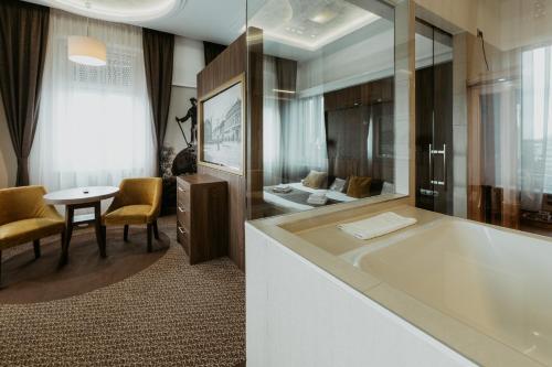 a bathroom with a large tub and a table at Duna Wellness Hotel in Baja