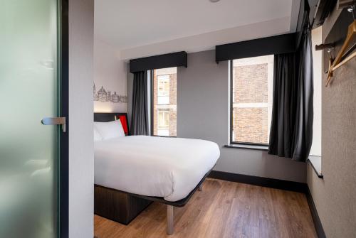 a bedroom with a bed and two windows at easyHotel Oxford in Oxford