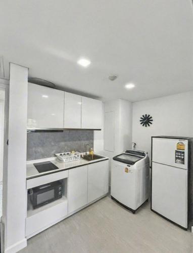 a white kitchen with a stove and a refrigerator at Mykonos Hua Hin - 1 bdr Condo Shared Pool Downtown in Hua Hin
