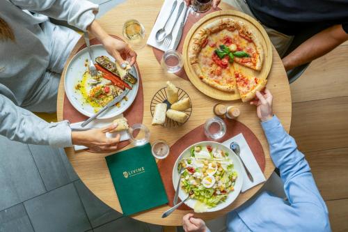 a group of people sitting around a table with pizza at INNSiDE by Meliá Paris Charles de Gaulle Airport in Roissy-en-France