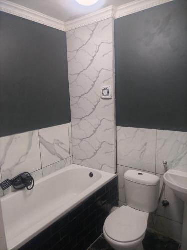 a bathroom with a toilet and a tub and a sink at Beach Vibes Villa in Cape Town