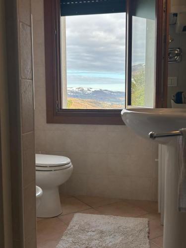 a bathroom with a window and a toilet and a sink at Casa Belvedere in Lizzano in Belvedere