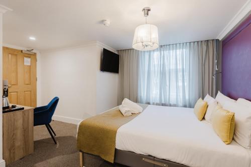 a hotel room with a large bed and a desk at The Porchester Hotel in London