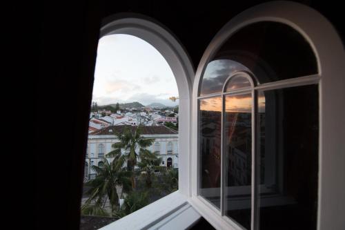 an open window with a view of a city at Casa das Palmeiras Charming House - Azores 1901 in Ponta Delgada