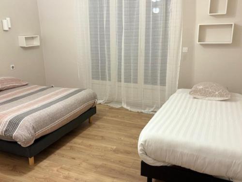 Appart F2 spacieux proche Paris في شمبلي: غرفة نوم بها سريرين ونافذة