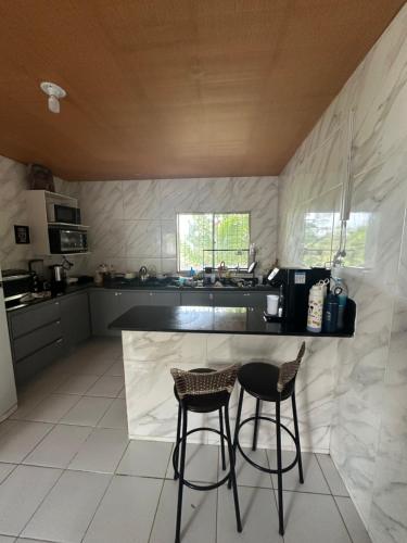 een keuken met 2 barkrukken en een aanrecht bij casa de campo em Aldeia PE in Recife