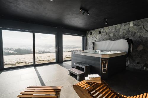 een badkamer met een bad, een bankje en ramen bij Tatres Bachledówka in Czerwienne