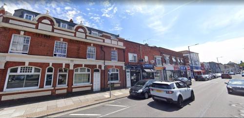 a city street with cars parked in front of buildings at The Fratton Apartment with parking in Portsmouth