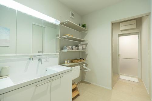 una cucina bianca con armadi bianchi e frigorifero di Hale Moana a Itoshima