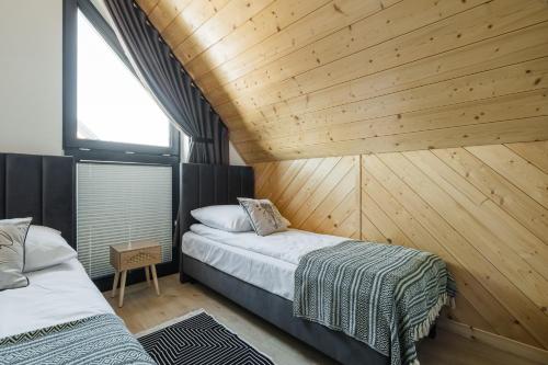 two beds in a room with a wooden wall at Tatres Bachledówka in Czerwienne