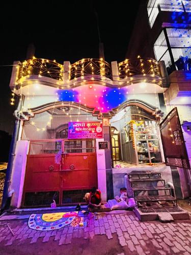 a couple of people laying in front of a building with lights at Radha Krishna Paying Guest House in Ayodhya