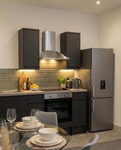 a kitchen with a table and a stainless steel refrigerator at City Centre Premier Executive Apartments in Sunderland