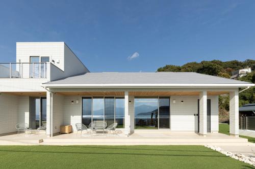 a white house with a porch with chairs on it at Hale Moana in Itoshima