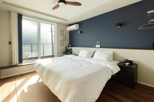 una camera da letto con un letto grande con una grande finestra di Hale Moana a Itoshima